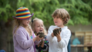 three kids playing in the mud outside of Waldorf School of the Peninsula