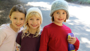 three elementary age girls smiling for a photo outside of Waldorf School of the Peninsula