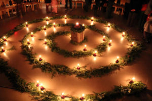 A spiral of greens large enough for people to walk in-between them, lit by apples holding candles.