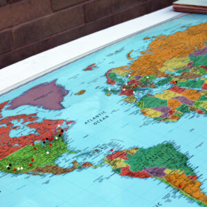 Flat map of the world with pins in it.