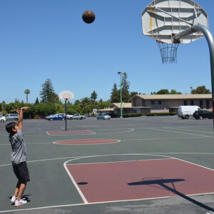 middle school student shooting a basketball at a hoop
